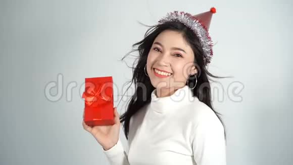 带着帽子拿着一个红色圣诞礼品盒的快乐女人的慢动作视频的预览图