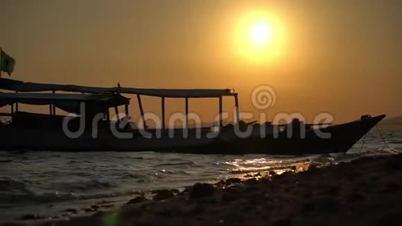 美丽的视频日落在海滩停泊的船近海岸模糊的光线黄昏太阳从地面拍摄视频的预览图