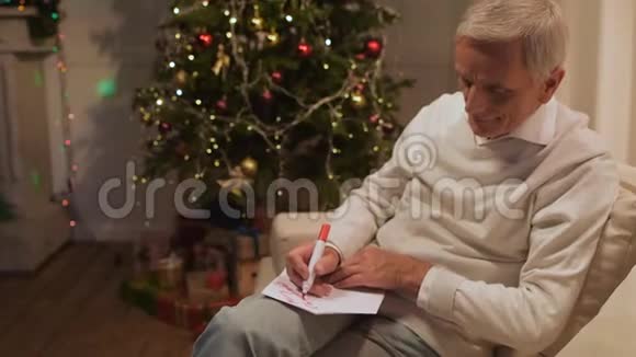 令人愉快的退休男子在圣诞卡上签名视频的预览图