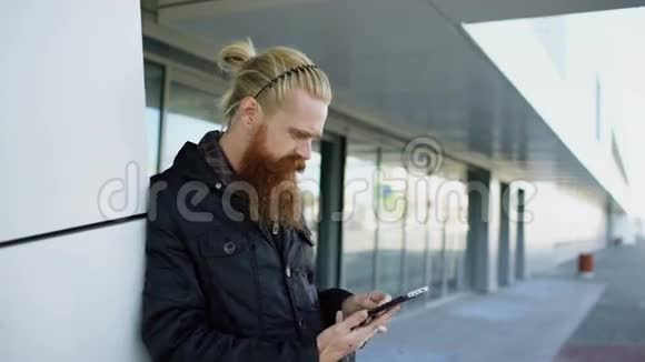 年轻的留胡子的嬉皮士使用智能手机上网在菲菲斯大厦附近视频的预览图