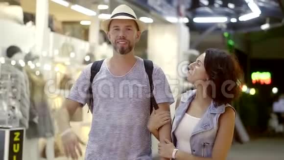 一个快乐的男人和女人在夜市里散步一对夫妇度假去购物他们选择纪念品和视频的预览图