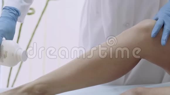 特写美容师用滑石粉准备腿部脱毛4k视频的预览图