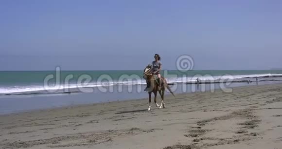 阳光明媚的日子里一个骑在沙滩上的女人视频的预览图