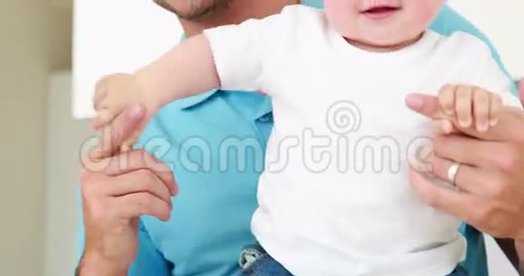 微笑的父亲帮助他的小男孩站起来视频的预览图