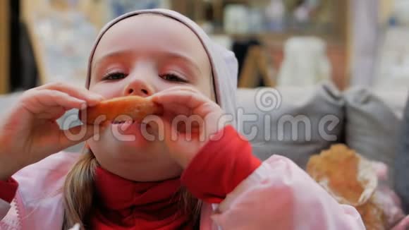 小女孩在咖啡馆里吃美味的甜甜圈视频的预览图