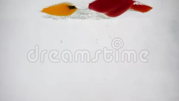 新鲜胡椒和西红柿在水中滴下慢动作特写视频的预览图