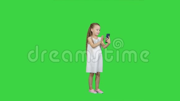 可爱的小女孩使用智能手机在绿色屏幕上大笑色度键视频的预览图