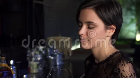 靠近一位美丽的黑发女郎在酒吧边喝着酒微笑着对着镜头视频的预览图