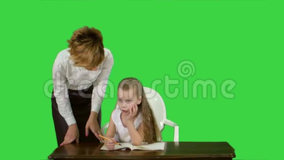 妈妈在绿色屏幕上帮女儿做作业彩色钥匙视频的预览图