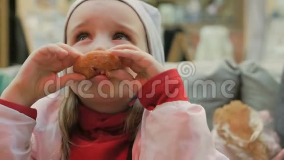 小女孩在咖啡馆里吃美味的甜甜圈视频的预览图