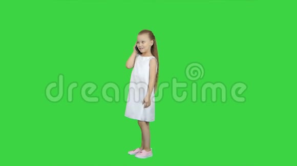 快乐的小女孩在绿色屏幕上用手机说话色度键视频的预览图