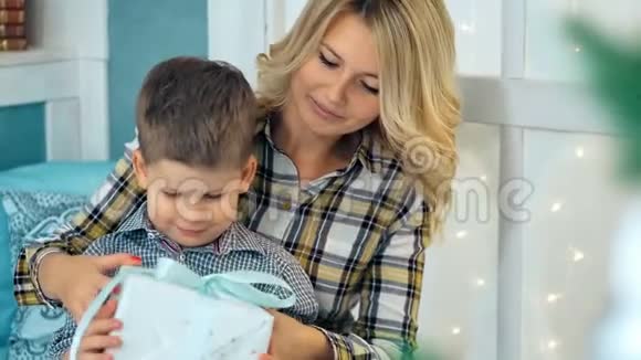 快乐小男孩打开圣诞礼物盒和妈妈视频的预览图
