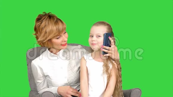 小女儿打电话坐在她母亲旁边的绿色屏幕上Chroma键视频的预览图