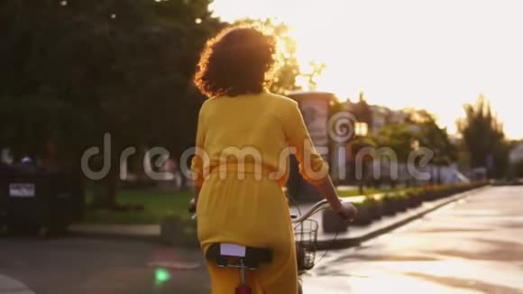 黎明时分一位不可辨认的妇女骑着一辆自行车在市中心骑着篮子和鲜花视频的预览图