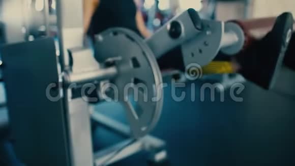 运动中年妇女在健身房的模拟器上泵腿肌肉4千克视频的预览图