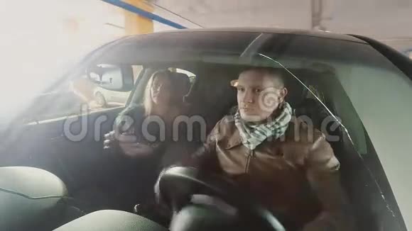 男人和女人笑着坐在车里透过车窗看着一辆车摄像头贴在前保险杠上视频的预览图