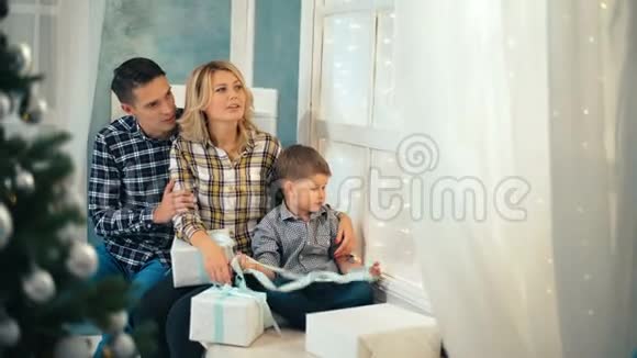 幸福的家人坐在家中圣诞树附近的窗台上视频的预览图