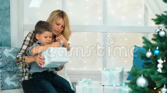 快乐小男孩打开圣诞礼物盒和妈妈视频的预览图