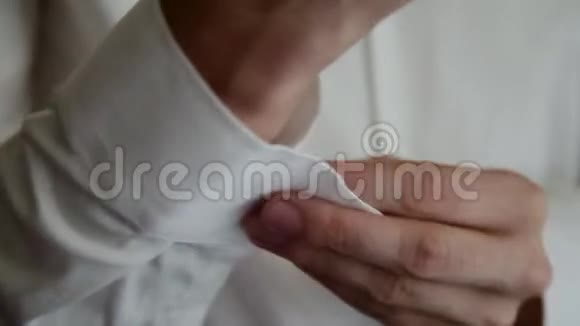 年轻人把袖扣放在白色衬衫上视频的预览图