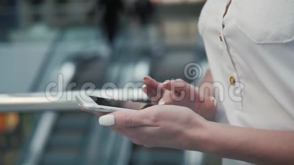 年轻女性在手机上查看数据的特写镜头短信应用机场候机楼购物中心视频的预览图