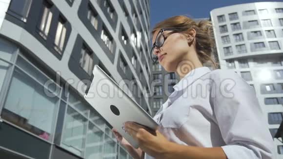 女商人在公司大楼附近持有平板电脑视频的预览图