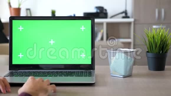 自由职业者在家里工作的笔记本电脑与绿色屏幕色度模拟视频的预览图