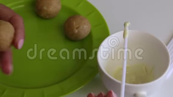 一个女人把她的棍子浸入融化的白巧克力中然后把它固定在饼坯里视频的预览图