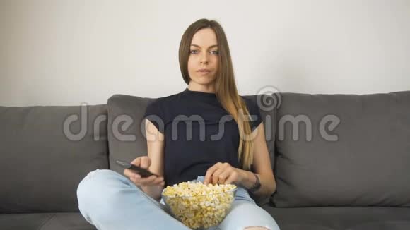 放松的女孩用爆米花看电视视频的预览图