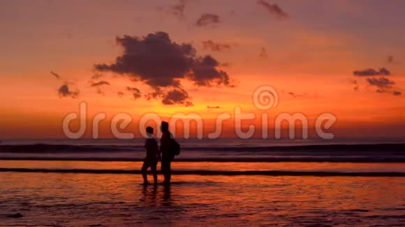 一对夫妇在美丽的日落中漫步在海滩上的剪影视频的预览图