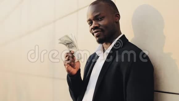 快乐的非裔美国商人手里拿着一大笔钱他站在办公室附近的街道上视频的预览图