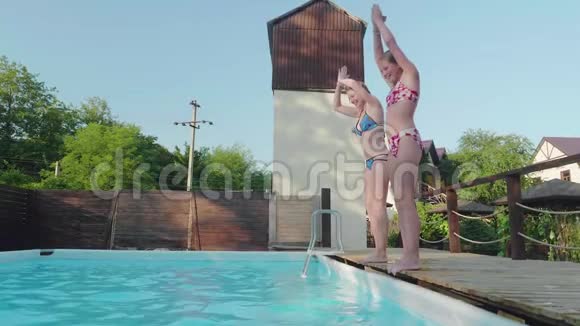 两个年轻快乐的金发女郎同步潜入室外游泳池慢动作视频的预览图