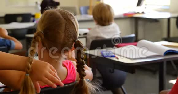高加索女学生在学校4k教室里坐在课桌前的后视镜视频的预览图