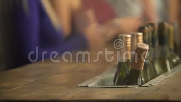 酒吧柜台有很多瓶酒酒吧气氛活跃女人带着电话视频的预览图