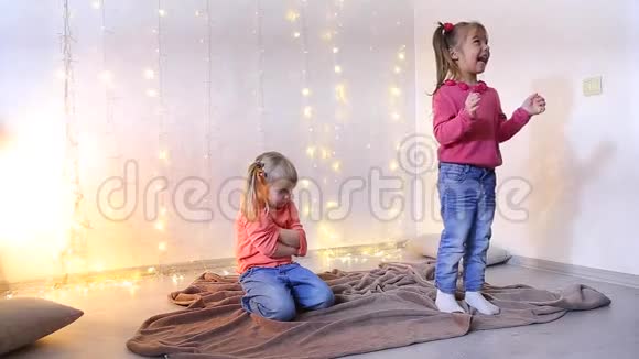 小女孩玩得开心为音乐跳舞第二个女孩坐在地板上生气视频的预览图