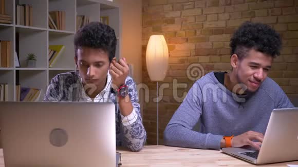印度和非裔美国男学生的特写镜头他们使用笔记本电脑的特写镜头视频的预览图