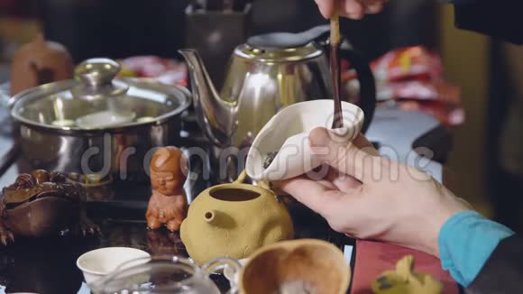 茶道主人用木勺把绿茶的叶子放进水壶里视频的预览图