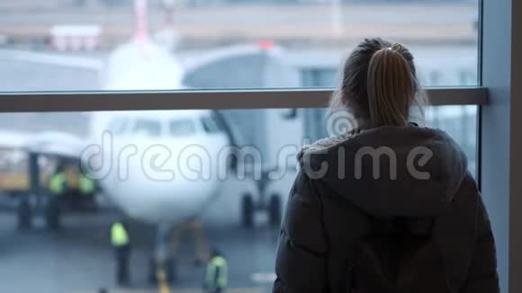 戴眼镜的年轻女孩或青少年戴着围巾看着机场的飞机拿着护照和机票视频的预览图
