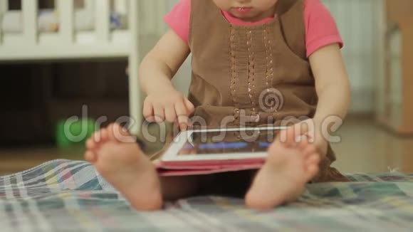 一个坐在地板上的小女孩用平板电脑触摸触摸屏上的手指视频的预览图
