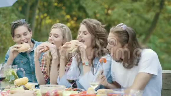 吃汉堡的朋友坐在户外聚会的餐桌上视频的预览图