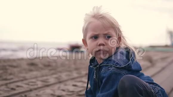 可爱的小女孩坐在岸边玩沙子她手里拿着沙子视频的预览图