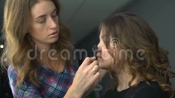 化妆师在模特脸上用刷子工作将色调应用于皮肤视频的预览图