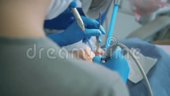 去看牙医的年轻女子医生与牙科护士治疗病人缩放和抛光牙齿视频的预览图