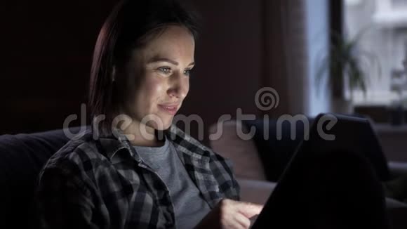 快乐的女人晚上用数码平板电脑视频的预览图