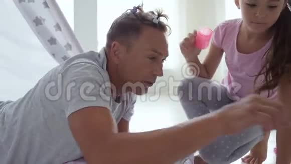 一个漂亮的小女孩在家里给她慈爱的父亲做发型视频的预览图