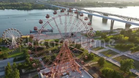 在河和城市景观上无人机可以看到游乐园里五颜六色的摩天轮大型摩天轮游乐园视频的预览图