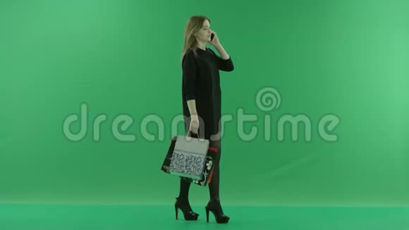 美丽的年轻女子购物后在智能手机上进行电话交谈颜色键绿色背景视频的预览图