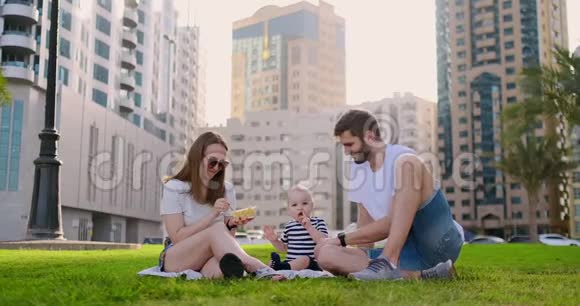 一家人坐在城里的草地上和一个小孩子一起笑视频的预览图
