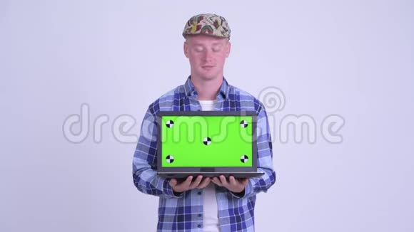 快乐的年轻英俊的时髦男人一边说话一边拿笔记本电脑视频的预览图