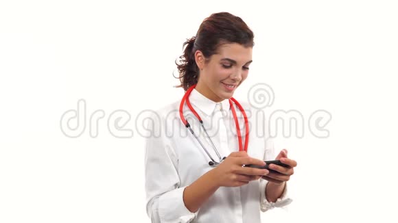 一位年轻护士用智能手机短信的肖像拥有听诊器和实验室的年轻医学专业人员视频的预览图