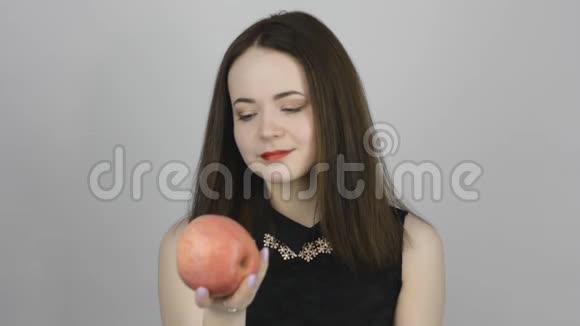 迷人的年轻女人吃着粉红色的苹果微笑着视频的预览图